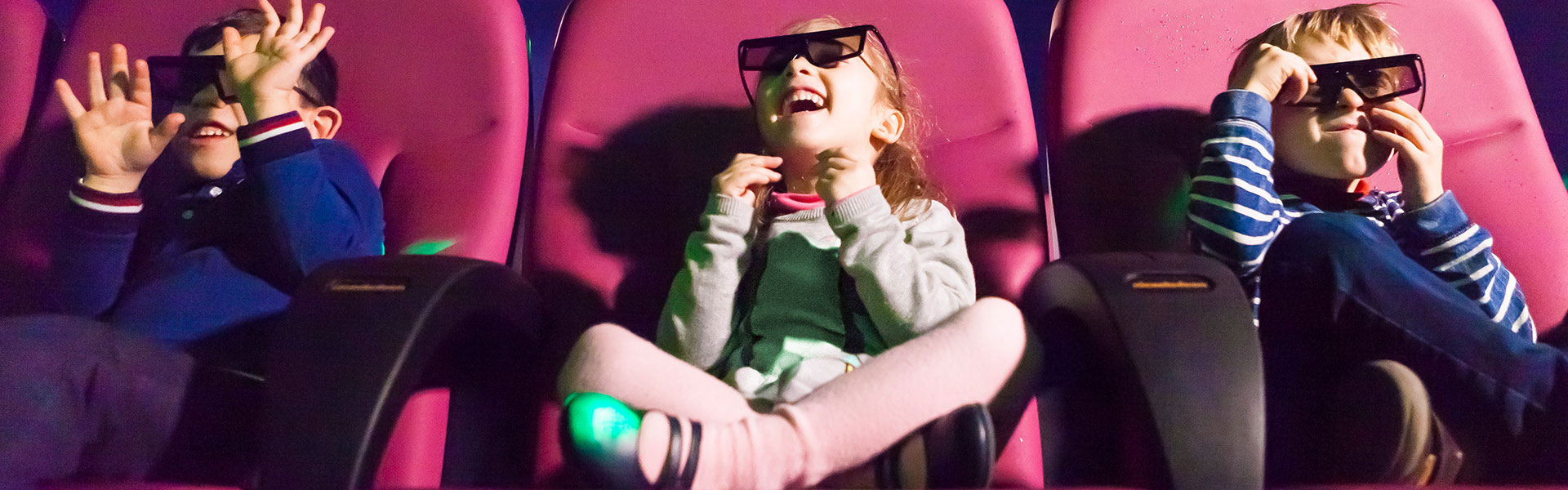 Three children in a movie theater with 3D glasses